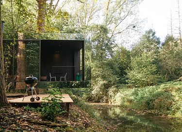Spiegel boslodge aan een riviertje